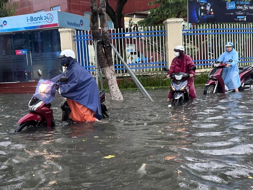 Ngã tư Nguyễn Văn Linh với Hàm Nghi bị ngập sâu trong nước, người dân phải dắt bộ phương tiện giao thông qua chỗ ngập sáng 25/9. (Ảnh: Trần Lê Lâm/TTXVN)