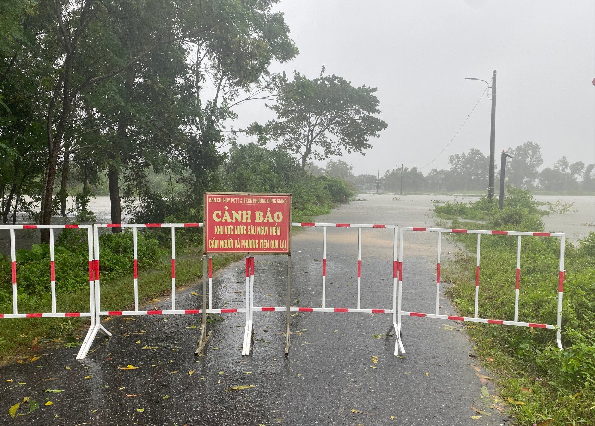 Ban Chỉ huy PCTT và TKCN phường Đông Giang, TP. Đông Hà lắp rào chắn, cắm biển cảnh báo khu vực nước sâu nguy hiểm, cấm người và phương tiện qua lại tại đập tràn Đại Độ 1 - Ảnh: N.B