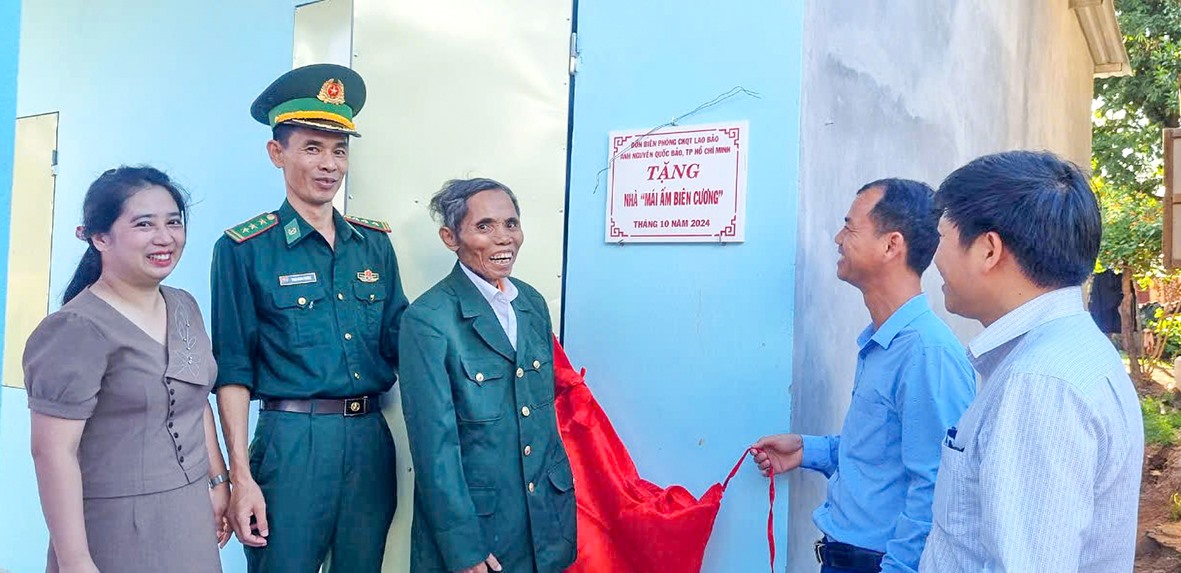 Ông Hồ A Tay (thứ 3, bên trái sang) phấn khởi vì được Đồn Biên phòng CKQT Lao Bảo và nhà hảo tâm xây tặng “Mái ấm biên cương” - Ảnh: L.T