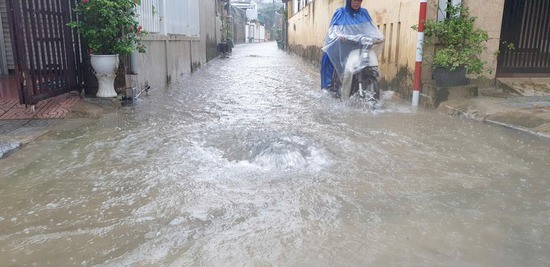 Nước làm bật một cống ở đường Tôn Thất Thuyết - Ảnh: Quang Hải