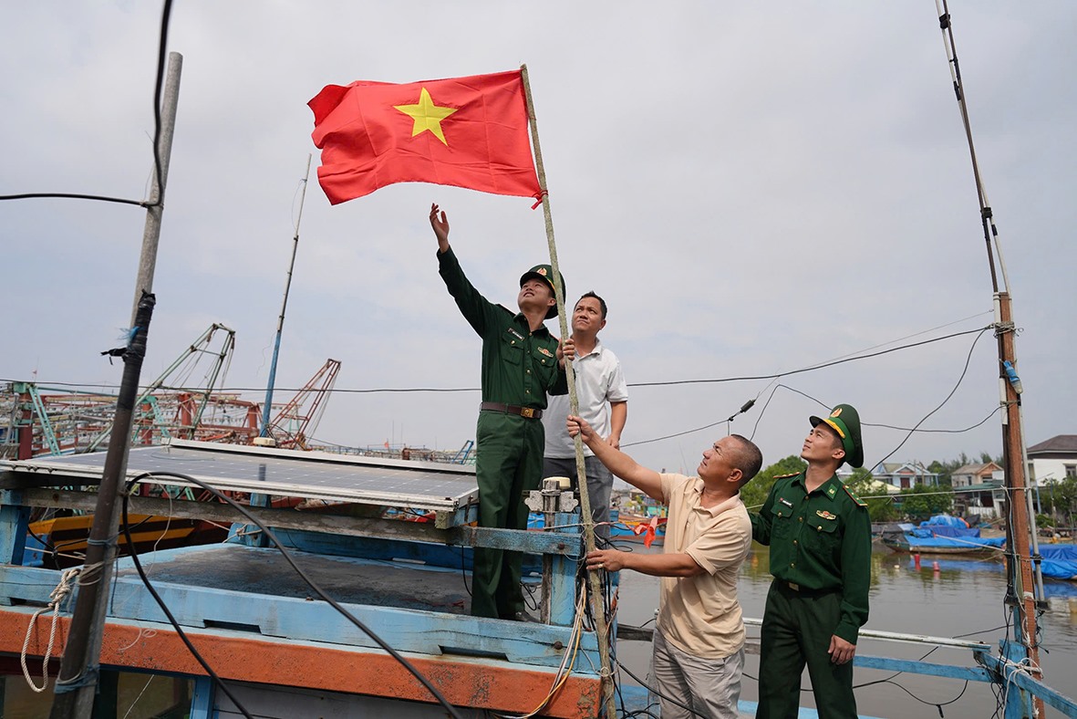 Cán bộ, chiến sĩ Đồn Biên phòng Triệu Vân tặng cờ Tổ quốc cho ngư dân - Ảnh: X.T