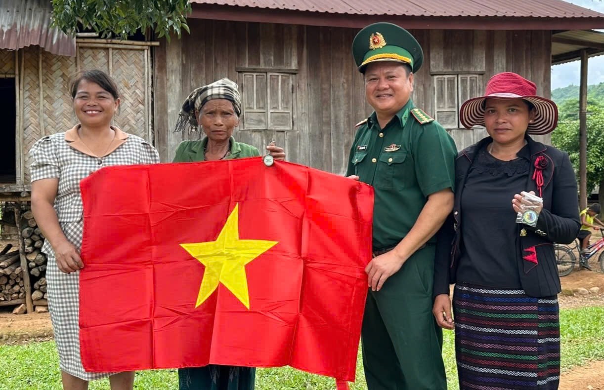 Bí thư Đảng ủy xã Hướng Lập Hồ Thị Thiệt (ngoài cùng bên trái) tặng cờ Tổ quốc cho người dân thôn Sê Pu - Tà Păng - Ảnh: T.H