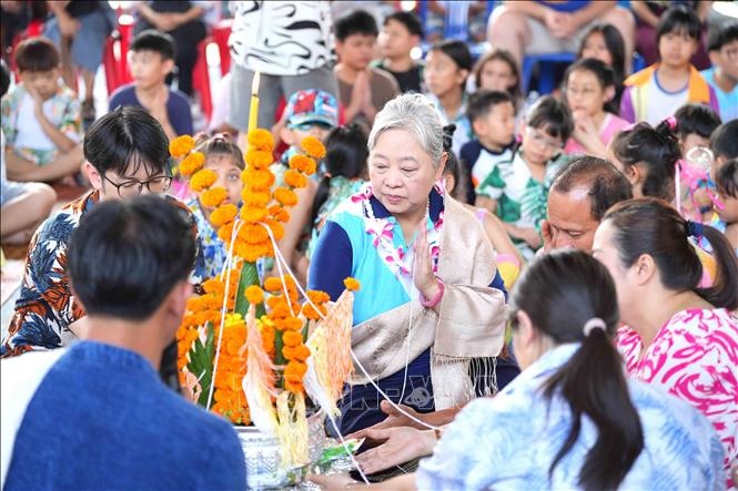 Thầy cô giáo cùng học sinh tại một trường học ở thủ đô Viêng Chăn tham gia lễ buộc chỉ cổ tay. Ảnh: Đỗ Bá Thành/PV TTXVN tại Lào