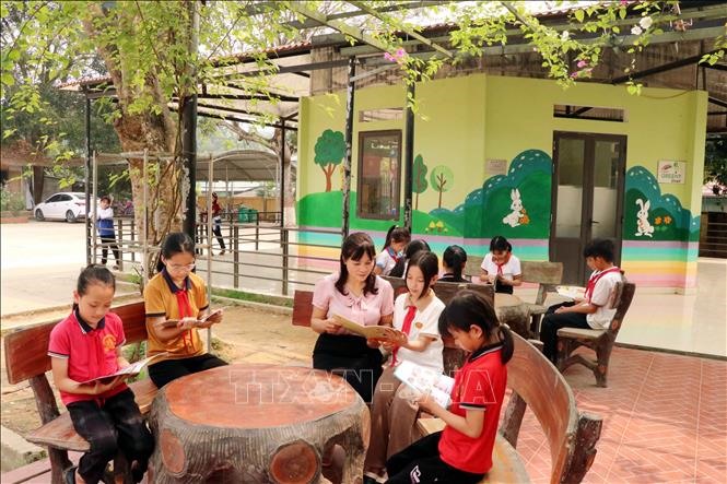 Học sinh đọc sách tại khu vực đọc ngoài trời của Thư viện Cầu vồng, Trưởng Tiểu học Tứ Quận, huyện Yên Sơn.