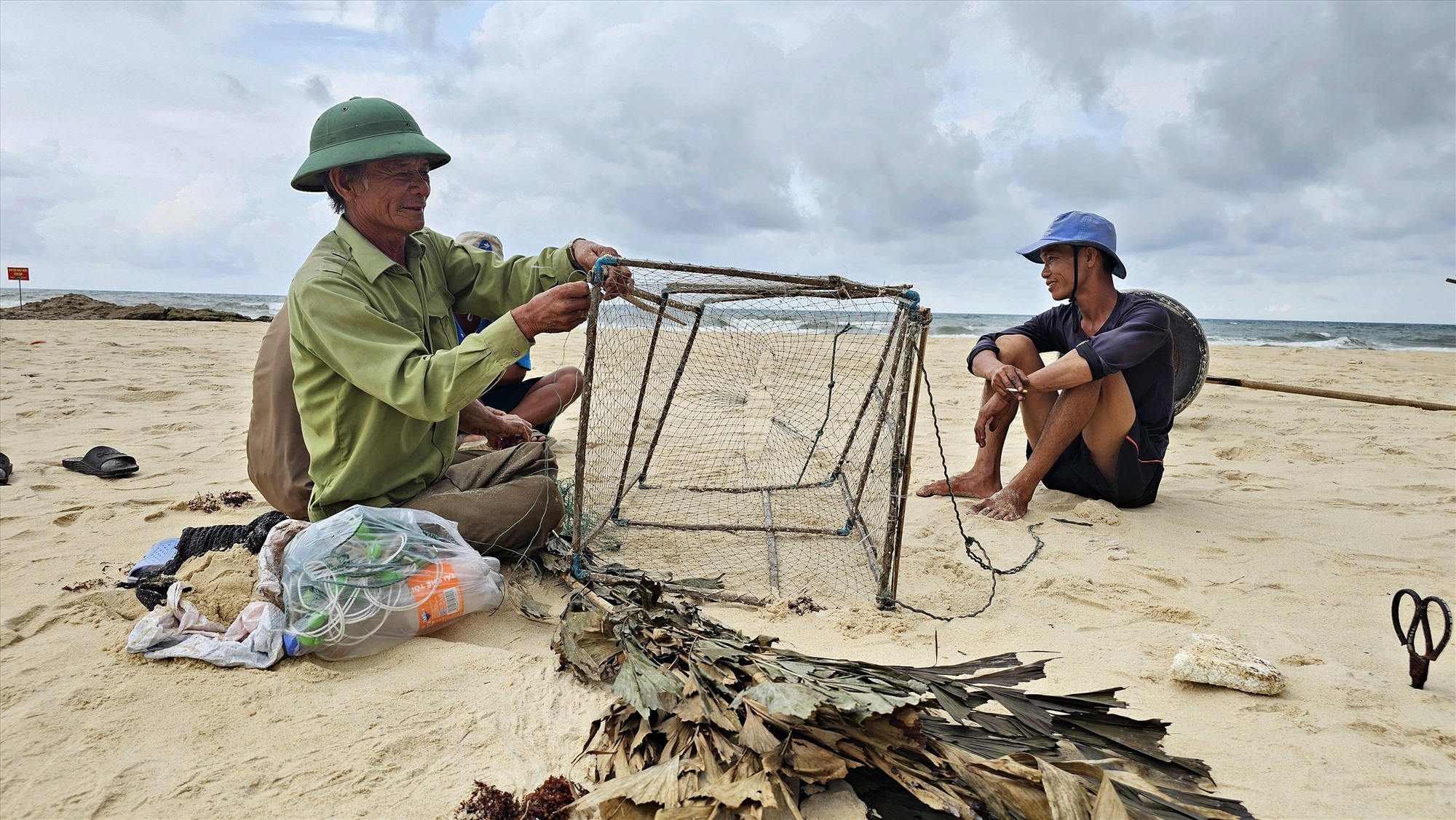 Ông Phan Thanh Tô, thôn Mỹ Thủy, xã Hải An, huyện Hải Lăng, sửa chữa chiếc lồng bẫy mực lá bị hư hỏng để chuẩn bị cho chuyến biển mới - Ảnh: L.A