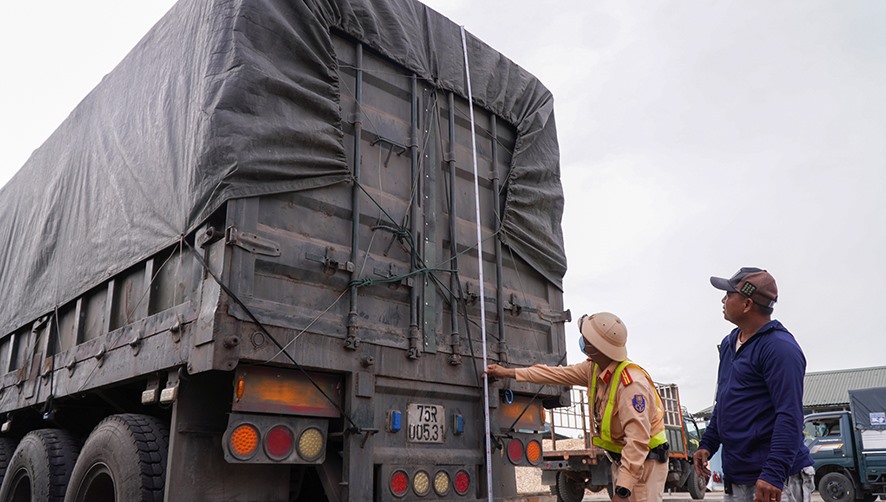 Lực lượng Trạm CSGT Đakrông kiểm tra kích thước thùng xe và hàng hóa trên xe container do anh Phạm Văn Pháp điều khiển - Ảnh: L.T