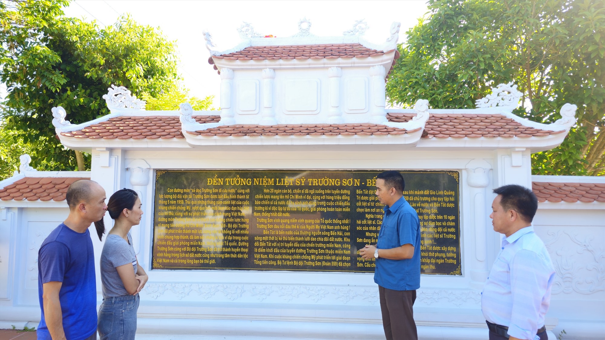 Anh Đào Thanh Dũng và Nguyễn Anh Tuấn (bên phải) thuyết minh cho vợ chồng anh Phạm Trung Kiên (TP. Hồ Chí Minh) tại Nhà bia tưởng niệm - Ảnh: TÚ LINH