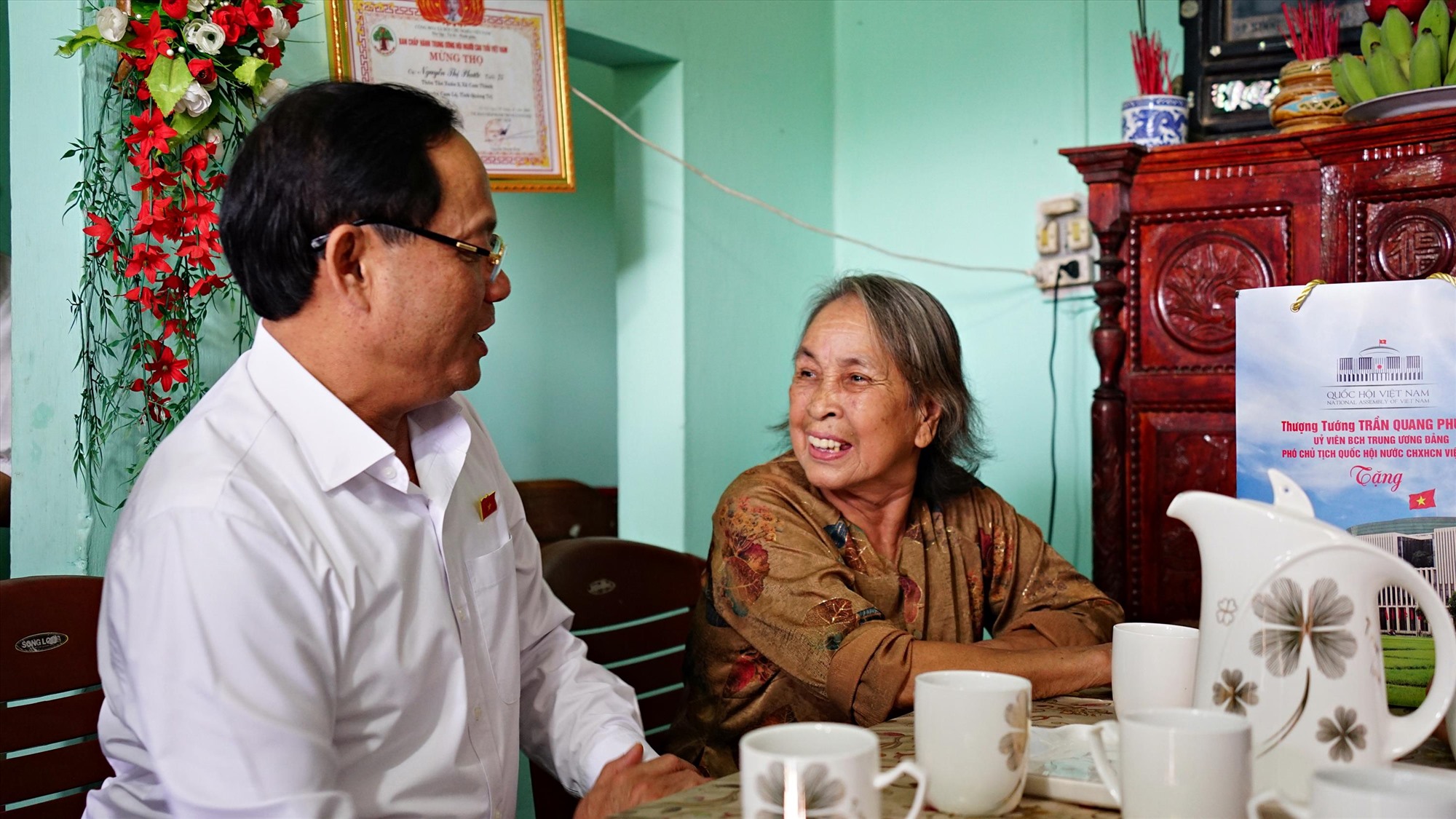 Phó Chủ tịch Quốc hội Trần Quang Phương thăm hỏi, trò chuyện với bà Nguyễn Thị Phước, vợ liệt sĩ ở tại thôn Tân Xuân 2, xã Cam Thành, huyện Cam Lộ - Ảnh: L.A