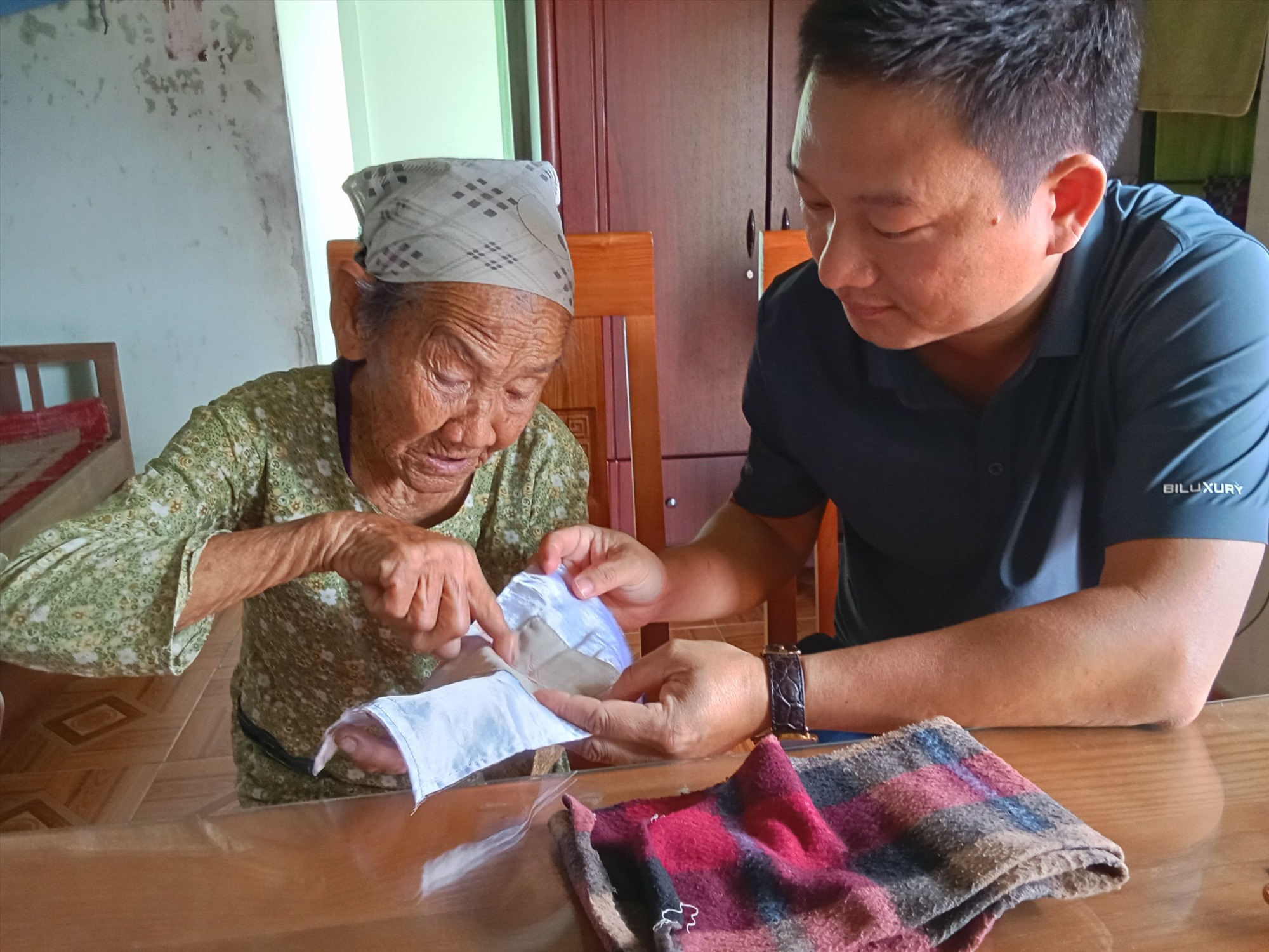 Cụ bà Phạm Thị Cháu lần mở chiếc khăn và chuyện trò về lời hẹn thề xưa vẫn còn nguyên vẹn - Ảnh: H.L