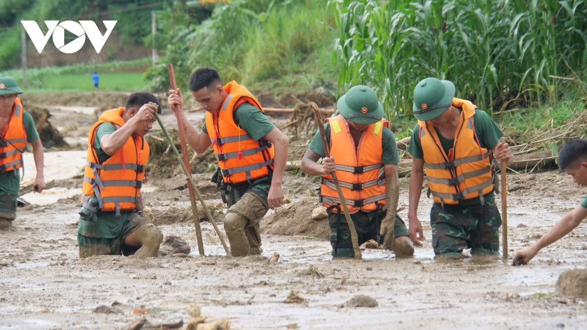 Dùng sào thăm dò độ sâu và tìm kiếm thi thể các nạn nhân nằm dưới lớp bùn lầy