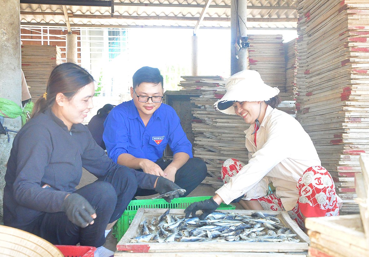 Anh Phan Đức Phước chuyện trò với người lao động để tìm hiểu, tháo gỡ những khó khăn trong việc hấp, sấy cá -Ảnh: Q.H