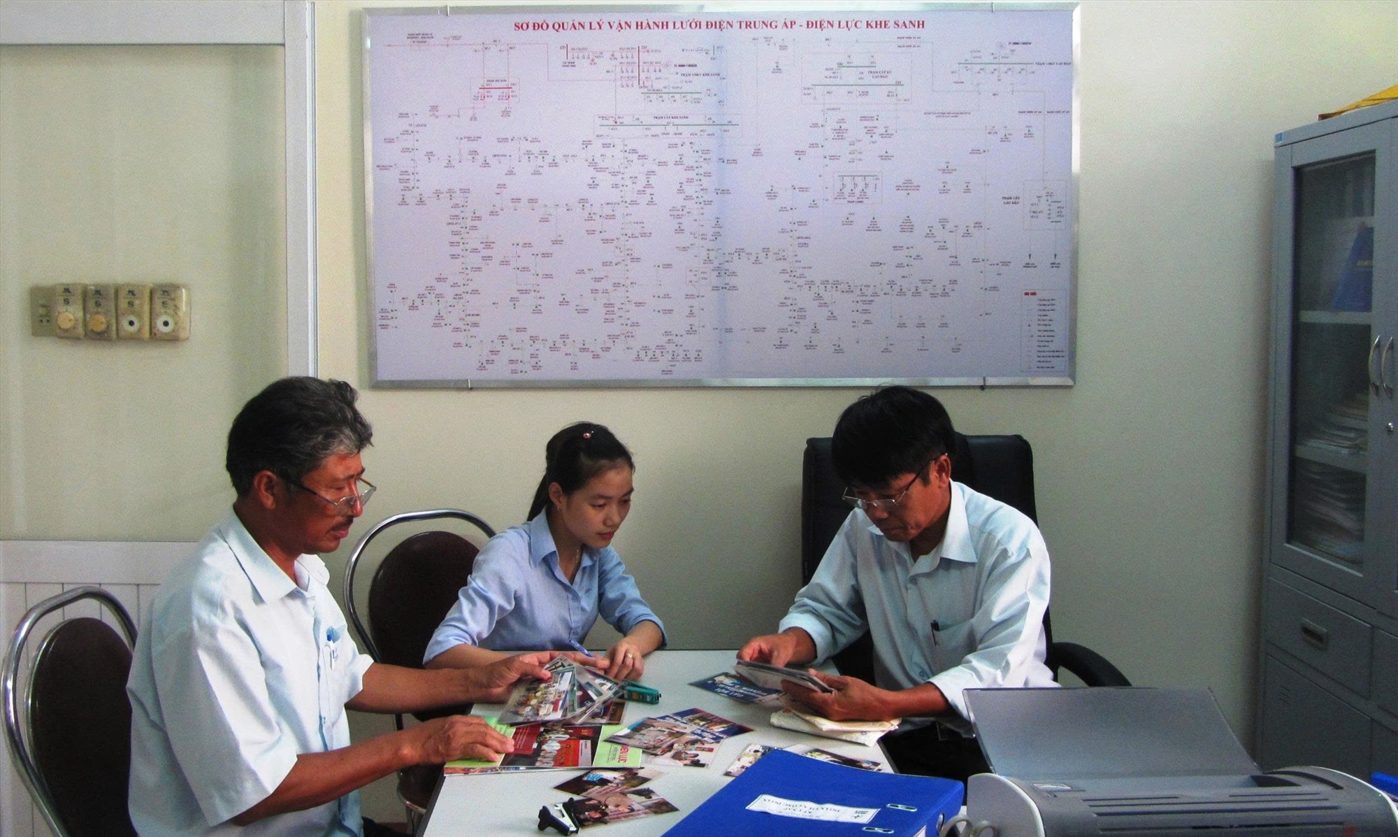Trần Nhi Nhi (giữa) tìm hiểu tư liệu để viết bài về quá trình xây dựng và phát triển của đơn vị Điện lực